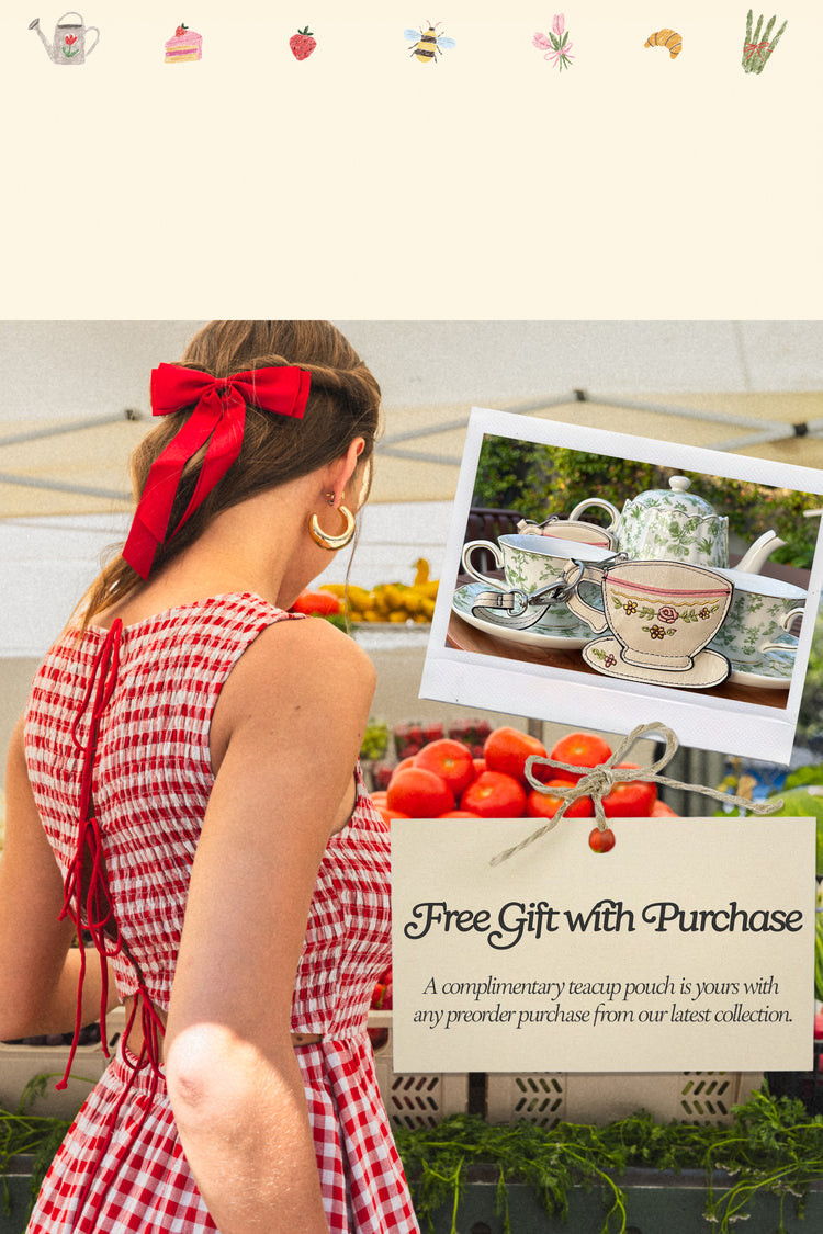 Woman in a red and white checkered dress with a red bow, standing in front of a display with teacups and a free gift offer.